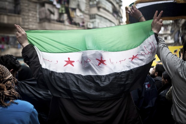 A Syrian carries a revolution flag during a Friday protest in Aleppo, Syria, where young people and children sang songs against Bashar Assad and the Syrian regime, Friday, Dec. 21, 2012.(AP Photo/Virginie Nguyen Hoang)