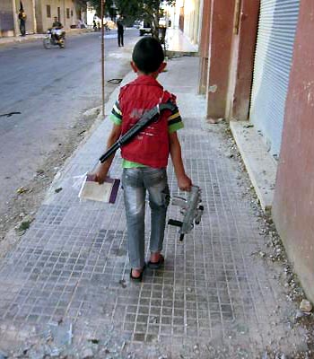 A boy carries toy guns in Al Qasseer city, near Homs. (R)