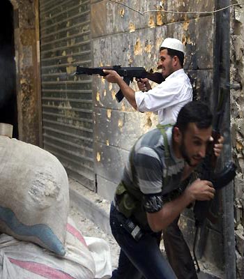 A Syrian rebel fires towards regime forces as his comrade ducks for cover during clashes in the old city of Aleppo in northern Syria. (AFP)