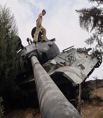 Boy walks on a damaged Syrian Army tank, belonging to forces loyal to Syria's President Bashar al-Assad, near Idlib. (R)