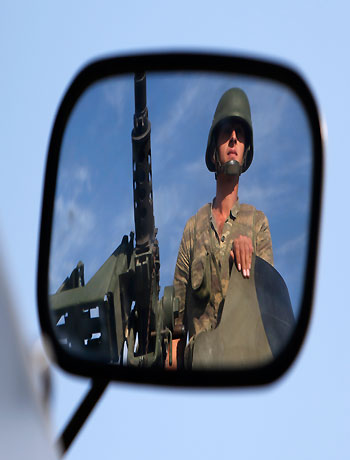 A Turkish soldier is reflected on a mirror as he stands guard on top of an armoured personnel carrier on the Turkish-Syrian border near the Akcakale border crossing, southern Sanliurfa province, October 4, 2012. (Reuters)