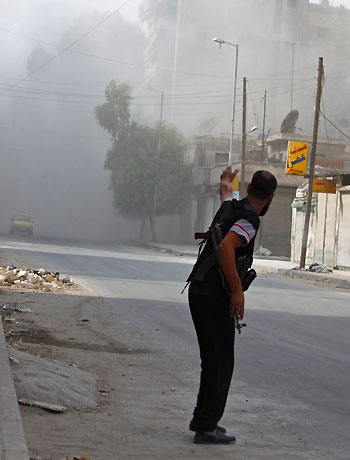 A Free Syrian Army fighter gestures at a car after a shell hit a street in Bustan Al-Basha, Aleppo. (Reuters)