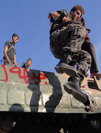 A member of the Free Syrian Army jumps form a military vehicle in Saraqib area near Aleppo in northern Syria October 12, 2012. (Reuters)