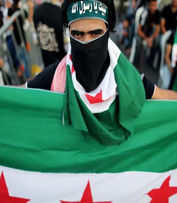 A Free Syrian Army supporter holds and covers his face with a the Syrian revolutionary flag during an anti-Syrian regime demonstration in downtown of Beirut.(AP)