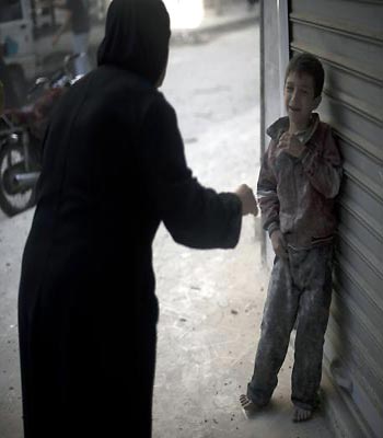 A frightened child stands in the street after a Syrian government artillery shell destroyed his family home in the Shaar neighborhood of the northern city of Aleppo. (AFP)