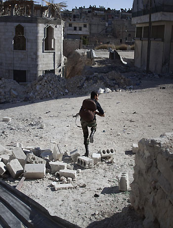 A Syrian rebel fighter runs to cover from a government sniper during the clashes at Suleiman al-Halabi neighbourhood in the northern city of Aleppo on October 18, 2012. (AFP)