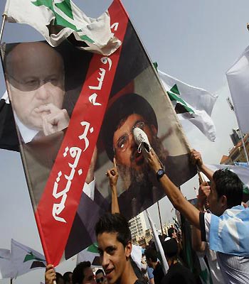 A supporter of the March 14 movement puts his shoe on a picture of Hezbollah’s Hassan Nasrallah and Prime Minister Najib Mikati during the funeral of General Wissam al-Hassan in downtown Beirut. (AFP)