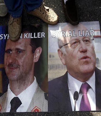 Supporters of the March 14 movement stand on a picture of Assad and Lebanese Prime Minister Najib Mikati during the funeral of General Wissam al-Hassan. (AFP)