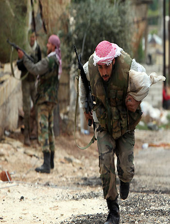 A member of the Free Syrian Army runs along a street to avoid sniper fire during fighting against pro-government forces in Harem town, Idlib Governorate, October 25, 2012. (Reuters)