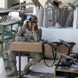 In this picture released by the US Marine Corps, Nov. 14, 2005, an Iraqi Army soldier relaxes after locating a weapons cache in a school allegedly occupied by insurgent forces, in Karabilah, Iraq, Friday, Nov. 11, 2005 (AP)