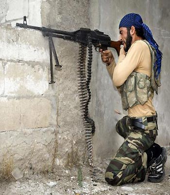 A rebel fighter fires his machine-gun at Syrian government troops at the citadel in the town of Harem, on the Turkish border. (AFP)
