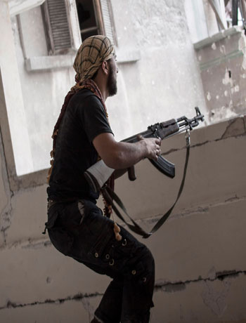 In this Wednesday, Oct. 31, 2012 photo, a rebel fighter prepares to fire on pro-government forces in the Karm al-Jebel neighborhood of Aleppo, Syria. (AP)