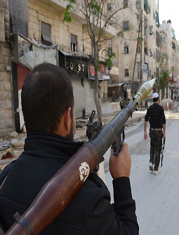 Armed rebel fighters walk along a deserted street at the front line as they battle pro-government Syrian troops in the Salaheddin district of the northern Syrian city of Aleppo, on October 30, 2012. (AFP)