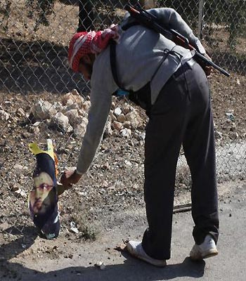 A Free Syrian Army fighter burns a picture he found of Hasan Nasrallah, for his support to Syrian President Bashar al-Assad, in Haram town. (R)