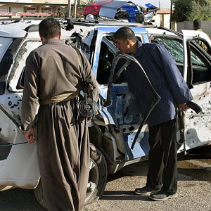 Iraqi policemen inspect the wreckage of a police car that was hit in a road side bomb in the city of Kirkuk, north of Baghdad, 15 November 2005 (AFP)