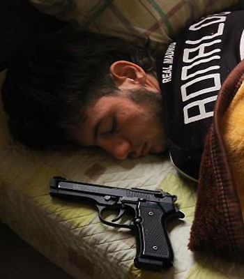Syrian opposition fighter, Bazel Araj, sleeps next to his gun in the northern city of Aleppo on November 11, 2012. (AFP)