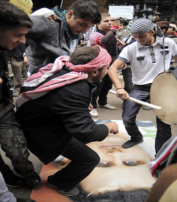 Syrian youth dance on a poster depicting President Bashar Assad during a demonstration against his regime in the Bustan al-Qasr district of Aleppo, Syria. (AP)