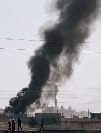 Residents of the Syrian town of Ras al-Ain run as smoke rises after an air strike on the town, as seen from the Turkish border town of Ceylanpinar. (Reuters)