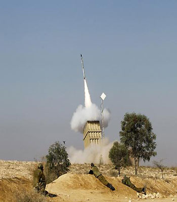Israeli soldiers watch as an Iron Dome launcher fires an interceptor rocket near Beersheba. (R)