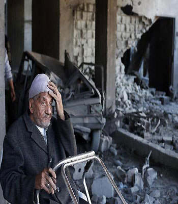 Palestinian man sits inside damaged house after Israeli air strikes in Gaza. (R)