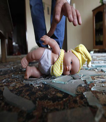 A Palestinian man picks up a doll lying on shattered glass in a damaged house following an Israeli air raid in Gaza City on November 17, 2012. (AFP)