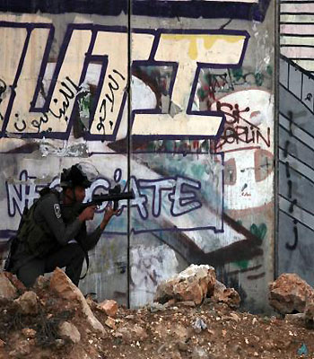 An Israeli soldier aims at Palestinian youth during a protest against the war on Gaza, at the Qalandia checkpoint, in the occupied West Bank, on November 16, 2012. (AFP)