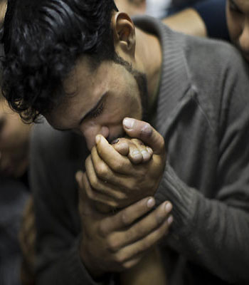 A Palestinian man kisses the hand of a dead relative in the morgue of Shifa Hospital in Gaza City, Sunday, Nov. 18, 2012. (AP)