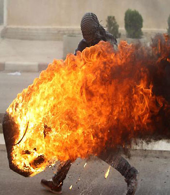 A Palestinian student pushes a burning tire during clashes with Israeli soldiers for the second consecutive day as they protest against the ongoing Israeli offensive on the Gaza Strip. (AFP)