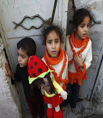 Palestinian children stand at the gate of their home as they watch the funeral procession of killed members of the Hejazi family, including two young children, in Beit Lahia, in the northern Gaza Strip. (AFP)