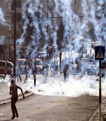 A Palestinian stone thrower runs from tear gas smoke fired by Israeli security forces (unseen) during clashes in the West Bank city of Bethlehem, on November 20, 2012. (AFP)
