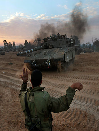 An Israeli soldier guides a tank to a new position at a staging area near the Israel Gaza Strip Border, southern Israel, Thursday, Nov. 22, 2012. (AP)