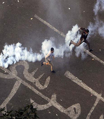 Protesters run away from tear gas with the characters "Leave Mursi" written under them in Cairo. (R)
