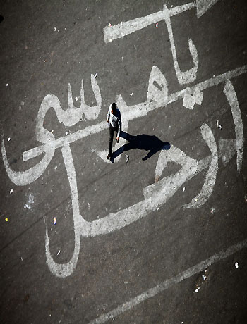 An Egyptian man walks over a graffiti reading "Morsi Go" on November 25, 2012 at Egypt's landmark Tahrir square in Cairo. (AFP)