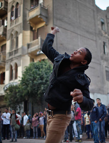 A protester throws stones at riot police during clashes at Tahrir square in Cairo November 26, 2012. (Reuters)