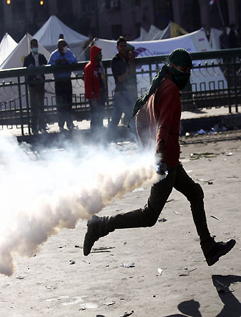 A protester throws back a tear gas canister during clashes with Egyptian riot Police on Tahrir Square on November 28, 2012 in Cairo. (AFP)