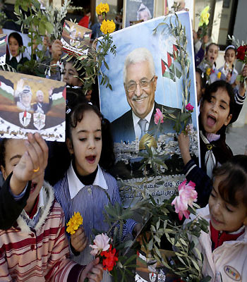 Palestinian schoolgirls hold pictures of President Mahmoud Abbas with Yasser Arafat, flowers and olive branches during a rally supporting the Palestinian UN bid for observer state status, in the city of Nablus. (AP)