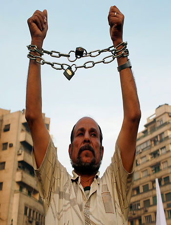 An anti-Mursi protester chains his hands, to symbolize the rule of the Muslim Brotherhood, as fellow protesters gather in Tahrir Square in Cairo November 30, 2012. (Reuters)