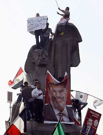 Supporters of Egyptian President Mohamed Mursi wave Egyptian national flags on top of a statue called "Egypt's Renaissance", at Cairo University during a rally in Giza, on the outskirts of Cairo December 1, 2012. (Reuters)