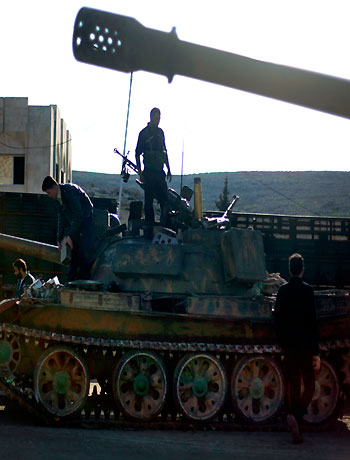 In this Monday, Nov. 19, 2012 file photo, Syrian fighters stand on a tank they took after storming a military base in Aleppo. (AP)