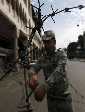 A soldier pulls barbed wire on a fence to close the road before a demonstration, in front of the presidential palace in Cairo, December 4, 2012. (Reuters)