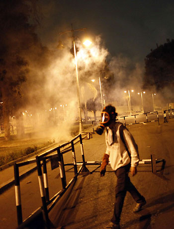 Demonstrators walk passed downed barriers placed outside the Egyptian Presidential Palace's main gate as security members throw tear gas during a demonstration on December 4, 2012 in Cairo. (AFP)