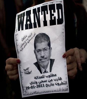 A protester carries a poster with a picture of president Mursi that reads "wanted for justice, escaped from the Natroun valley prison in January 29, 2011, Reward, a box of oil and two eggs" in Cairo(AP)