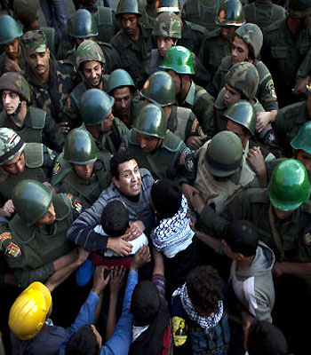 Egyptian protesters push army soldiers standing guard in front of the presidential palace in Cairo, Egypt. (AP)