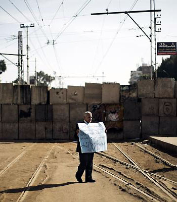 A protester opposed to Egypt's Islamist president holds up a placard in front of a barricade erected by the Egyptian army to protect the Presidential palace in Cairo. (AFP)