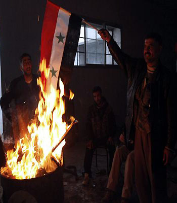 A Free Syrian Army fighter poses as he burns a Syrian flag in Ouwayjah village in Aleppo. (R)