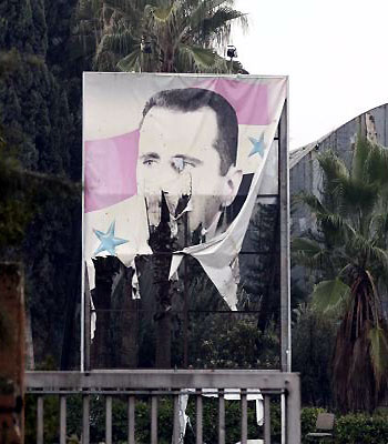 A torn poster of Syria's President Bashar al-Assad is seen at the entrance of a factory in Ouwayjah village in Aleppo. (R)