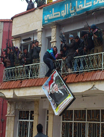 Free Syrian Army fighters from Al-Farooq battalion remove a poster of Syria's President Bashar Al-Assad from a military hospital after the fighters said they fought and defeated government troops in Halfaya, near Hama December 18, 2012. (Reuters)