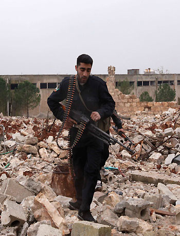 Free Syrian Army fighters carry their weapons as they walk on rubble in Ouwayjah village in Aleppo December 17, 2012. (Reuters)