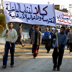 Iraqi men carry a banner that reads: "No to the Interior Ministry Wolf Brigade and No for its terrorist acts," during the funeral procession of  Wathiq Abdullah al-Kadouri, a member of the Sunni Islamic party, northeast of Baghdad, 17 November 2005 (AFP)
