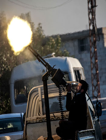 In this Saturday, Dec. 15, 2012 photo, A Free Syrian Army fighter fires a weapon during heavy clashes with government forces at a academy besieged by rebels north of Aleppo, Syria. (AP)